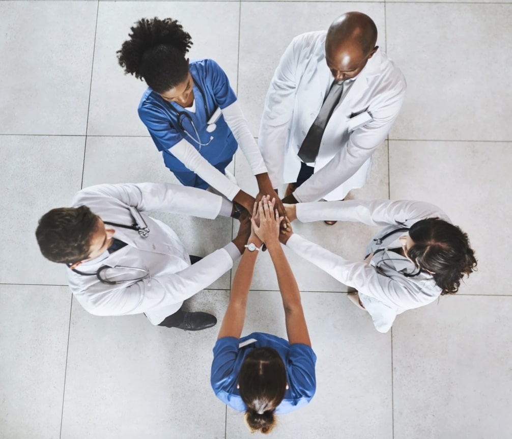 Doctors in a circle with hands in a huddle in Kingston, Ontario.